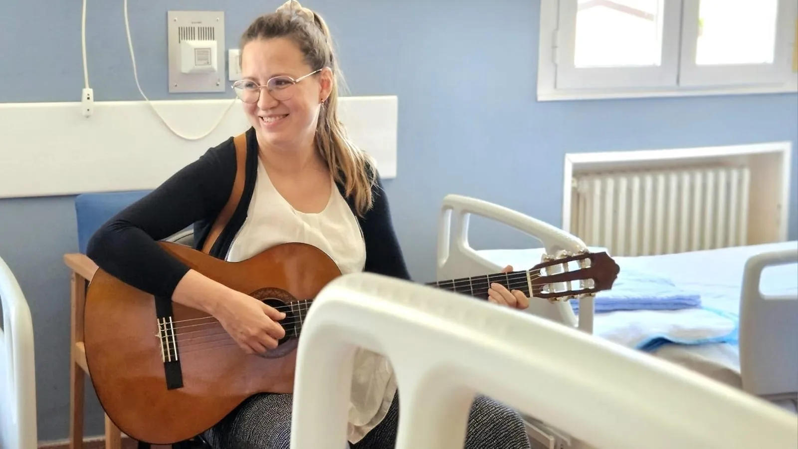 Musicoterapeuta de Concertino tocando la guitarra en una habitación de hospital