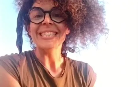 Mabi sonriendo, sentada en un prado verde